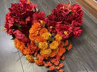 Top-down view of the red and orange artificial flower arrangement on a wood floor