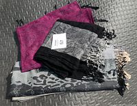 Two Pakshima scarves folded together, showing magenta and black grey beige animal print patterns with fringes.