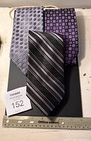 Three silk neckties laid flat for display showing full length and pattern variety with a ruler for size reference.