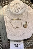 Sterling silver jewelry lot displayed on a white textured background with a ruler to show size.