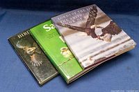 Three hardcover bird reference books stacked, showing their covers: 'Save the Birds', 'Birds of Prey', and 'Lords of the Air The Smithsonian Book of Birds'.