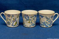 Three ceramic mugs showing side views with colorful folk art patterns by Lotte Turi for Figgjo.