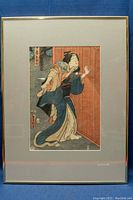 Framed full view of the Japanese woodblock print showing the woman's figure and red striped screen.