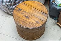 Top and side view of antique wooden cheese barrel showing wood grain and circular shape