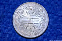 Obverse side of the Chinese silver coin showing dragons and a central emblem with stylized Chinese pattern.