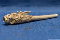 Side angle close-up showing detailed dragon head mouthpiece and tapered silver pipe body.