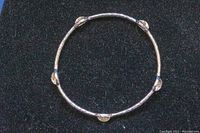 Top view of silver bangle showing circular form and placement of five clear stones.