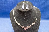 Full set showing necklace and earrings on display bust with blue background