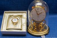 Miniature Mikimoto desk clock in original presentation box next to large Kundo glass domed mantel clock.