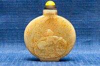 Front view of the carved jade opium snuff bottle showing embossed reclining figure.