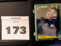 Photo displaying top hockey card featuring player Eric Lindros in full hockey gear, inside sealed plastic case with MaxSold lot number 173.