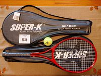 Two tennis racquets, one in its carrying case, with one tennis ball included, placed on a brown detail-patterned surface