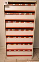 Front view of closed chest of drawers showing eight drawers with orange trim and labels.
