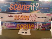 Three Scene It? DVD games stacked showing front box art: original 2003 version, The Simpsons themed, Disney Pixar themed