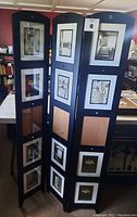 Full view of the black three panel folding picture holder with photographs displayed in photo slots.