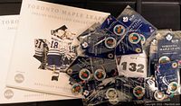 Two Toronto Maple Leafs 2002/03 Medallion Collection folders and 24 individually packaged medallions spread out, showing team branding and packaging.