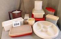 Photo showing various Tupperware containers including pitchers, trays, and storage boxes arranged on a surface.