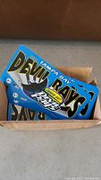 Box containing multiple stacked Tampa Bay Devil Rays vanity license plates with visible blue and black design.