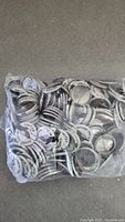 Clear plastic bag filled with numerous black-and-white metal pinback buttons.