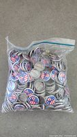Plastic zipper bag containing approximately 500 metal pinback buttons with peace sign design