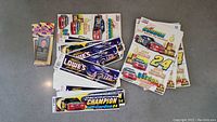 Vintage NASCAR bumper stickers and window clings stacked and spread on table, featuring predominantly Jeff Gordon designs and championship themes.