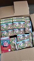 Box containing multiple boxes of MLB Folding Fans and a box of NFL Fingernail Tattoos