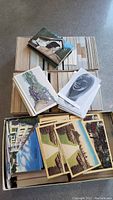 Wide view showing multiple boxes and stacks of postcards with assorted types and images.
