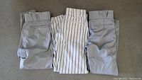 Three pairs of official New York Yankees game worn pants including two gray and one pinstriped pair laid flat on the floor.
