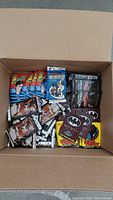 Box with mixed sealed trading card packs including 21 Jump Street, WWF, Batman, and Dead or Alive.