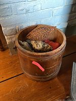 Front view of wooden bucket showing scratches, shape, and sachets inside.