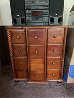 Front view of 12 drawer wooden cabinet with brass knobs and twisted wood column detailing on sides.