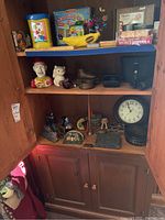 Full view showing shelf with bookends, clown bank, animal figurines, Westclox clock, Tasco binoculars, and other items.