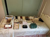 Full spread of vintage purses, gloves, hand fans, and parasol on a bed showing all items in the lot.