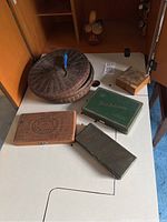 Photo shows round lidded woven basket with four boxes including green 'Lord Salisbury' box and wooden box, arranged on a white surface