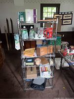 Front view of 6-tier stainless steel wire shelving unit filled with various household items including bottles, boxes, small appliances, and containers.