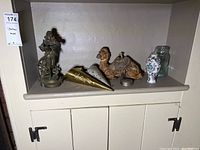Wide shot of antique camel ink well, bronze statue, decorative vases, and brass items on shelf