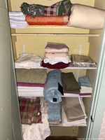 Shelves with assorted stacked towels, blankets, sheets, and linens in various colors and patterns.