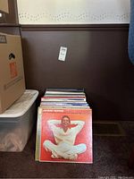 Photo showing a stack of vinyl records with Johnny Mathis album cover on top in red/orange color with man in white clothes seated and smiling.