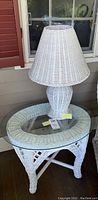 White wicker table lamp placed on the wicker table, showing tabletop and lamp shade details.