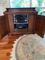 Full view of the wooden cabinet with open doors showing the stereo components inside.