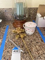Photo of large glass candle holder with wood base and visible blue candle inside, placed on a granite countertop.