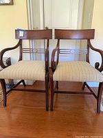 Front view of both mahogany dining arm chairs showing frames and upholstered seats