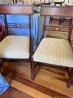 Front view of the two mahogany dining chairs showing the wood frame, geometric splat back, and upholstered seat fabric.