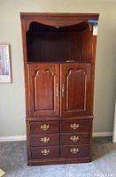 Front view of Thomasville traditional wooden shelf unit showing drawers, cabinet doors, and upper open shelf with light fixture.