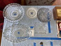 Top-down view of nine pieces of vintage Depression glassware, including three bowls and three plates, arranged on a table.