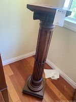 Full view of the wooden pedestal display stand showing fluted column and square base and top