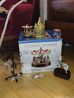 Photo showing Grand Carousel box with two small glass carousel musical boxes on top plus ceramic box and hand-painted hanging horses in front.