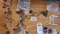 Top view of assorted costume jewelry spread on wooden table, including chains, earrings, and beaded pieces.