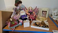 Photo of wizard doll, three winged fairy dolls, small stuffed unicorn, tiger figurine and butterfly tray on shelf