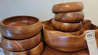 Full view of the wooden bowls stacked and arranged, showing various sizes with smooth polished wood of brown shades and rounded rims